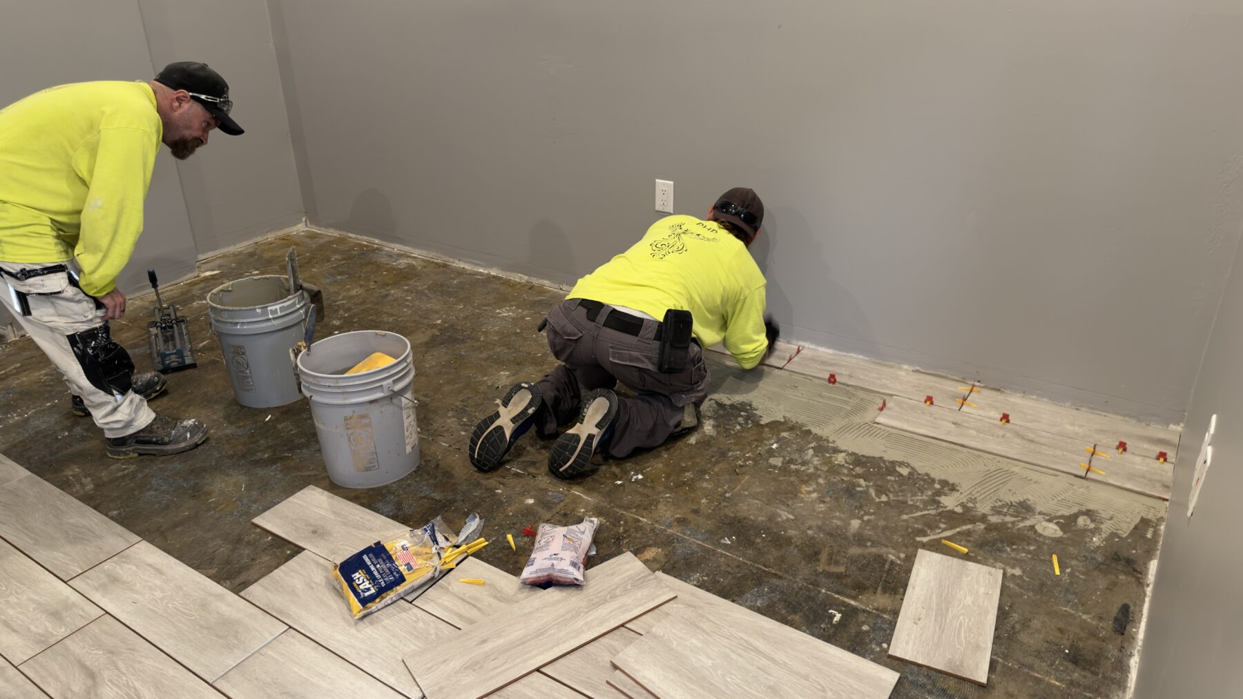 A PHP crew member positions flooring along the office wall while a colleague assists.