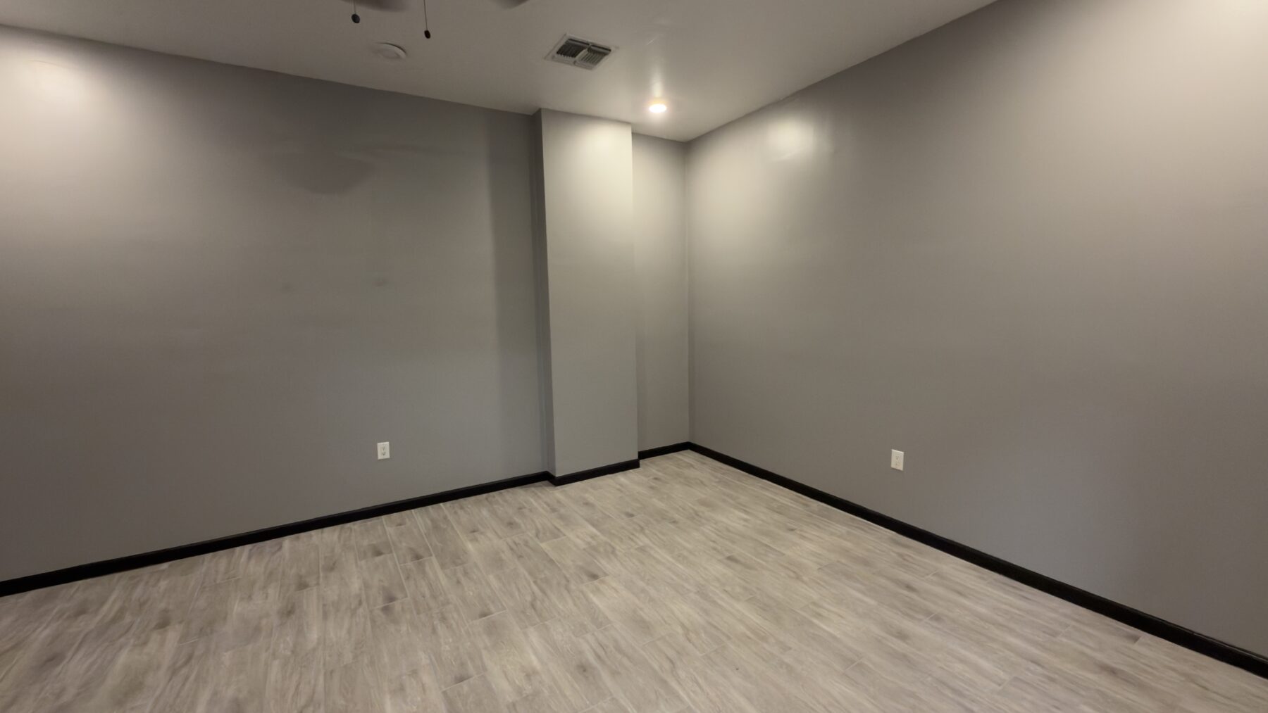 The renovated office with gray walls, new flooring and black baseboards before furniture is added.